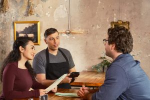 Konobar s POS uređajem poslužuje goste u restoranu